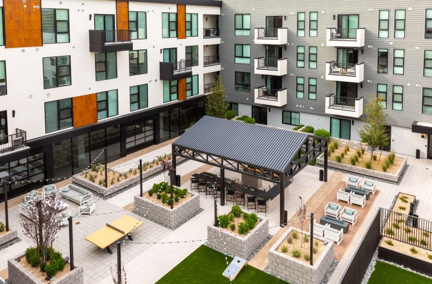 Aerial view of a modern apartment complex courtyard with a metal pergola, seating areas, and raised garden beds.